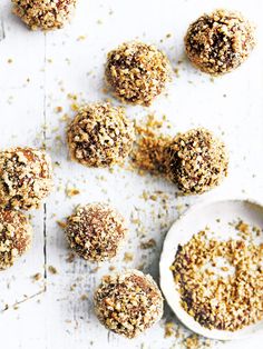 several balls of food sitting on top of a white surface next to a bowl and spoon