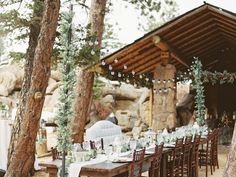 an outdoor dining area with tables and chairs set up in front of some large rocks