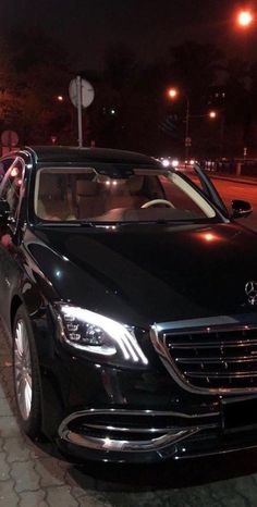 a black car parked on the side of the road at night with people in it