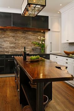 a kitchen with white cabinets and wooden counter tops, an island in the middle has fruit on it