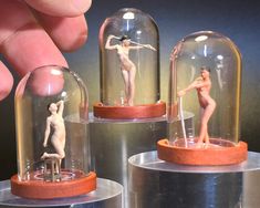 there are three miniature figurines in glass domes