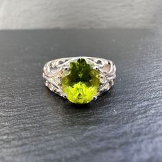 A stunning 9ct white gold vintgage peridot and diamond ring featuring a large ocal cut beautifully faceted green peridot gemstone claw set with each side flanked by a small round cut diamond leading on to a very fancy filigree design scrolling ornate open shoulders blended to a smooth tapering band. Birmingham Hallmarks. The ring is a UK size N - US Size 6.75 which can be resized a few sizes. Classic Lime Green Oval Jewelry, Oval Peridot Gemstones For Anniversary, Oval Lime Green Rings For Anniversary, Lime Green Oval Rings For Anniversary, Lime Green Oval Rings With Accent Stones, Oval Lime Green Anniversary Ring, Elegant Lime Green Oval Rings, Lime Green Oval Rings Fine Jewelry, Oval Lime Green Fine Jewelry Ring