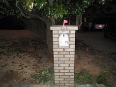 a brick mailbox sitting in the middle of a yard next to a large tree