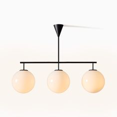 three white balls hanging from a black metal bar with two lights on each end and one light above them