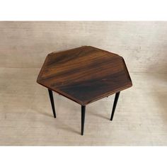 a wooden table with black legs and a hexagonal shape on the top, against a white background