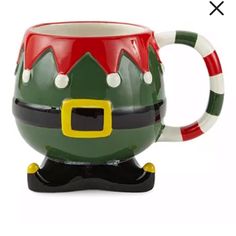 a green and red coffee mug with a santa hat on it's head,