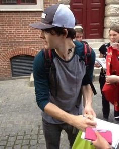 a man in a hat and backpack walking down the street with other people behind him