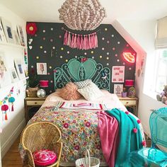 a bedroom decorated in pink, blue and green with a chandelier hanging from the ceiling