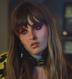 a close up of a person with long hair and piercings on her nose, wearing an animal print shirt