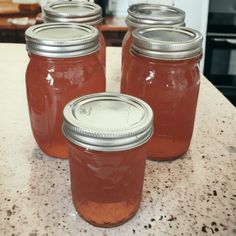 four jars filled with liquid sitting on top of a table