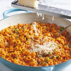 a pan filled with pasta and cheese being sprinkled on top of the skillet