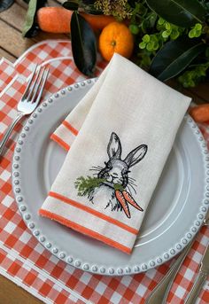 an orange and white checkered table cloth with a rabbit drawn on the napkins