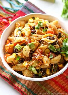 a white bowl filled with pasta salad on top of a red and green table cloth