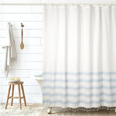 a white and blue shower curtain next to a bath tub with a wooden stool in front of it