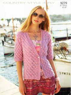 a woman in pink sweater and shorts standing next to water