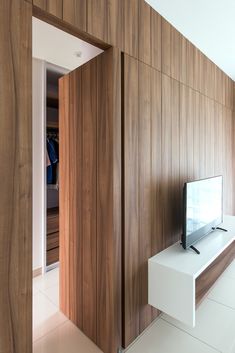 a tv sitting on top of a white shelf next to a wooden paneled wall