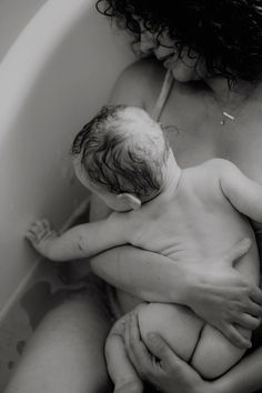 a woman holding a baby in a bathtub