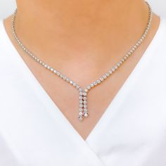 Elevate your style with this Graceful Diamond Tassel Necklace Set. Crafted with 18k white gold and 2.94ct diamonds in round shape, this set has a set length of 17" and a drop length of 1". It features a push lock with clasp and comes with matching earrings. The necklace has a weight of 30.8g, making it a perfect addition to your high fashion wardrobe. PRODUCT DETAILS Gold Purity(karat): 18k Item Weight(grams): 30.8 Item Finish: White Gold Stone: Diamond Diamond Weight(carats): 2.94ct Diamond Col Elegant Drop Necklace With Hand Set Details, Elegant Hand Set Drop Necklace, Dazzling Formal Drop Diamond Necklace, Elegant Diamond Cut Drop Necklace In Diamond White, Elegant Diamond-cut Drop Necklace In Diamond White, Elegant Diamond White Drop Necklace With Diamond Cut, Elegant Diamond White Drop Necklace, Elegant Diamond Drop Necklace For Anniversary, Formal Diamond Drop Necklace