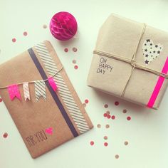 two wrapped presents sitting on top of a table next to a pink ornament