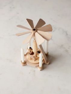 a small wooden windmill with candles in front of it on a marble counter top,