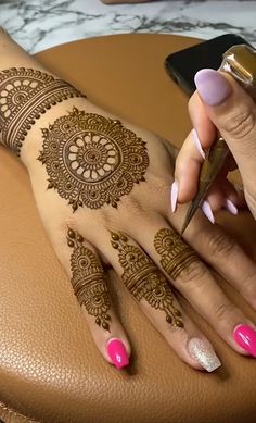 a woman with henna on her hand holding a pair of scissors