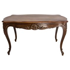 a wooden table with carvings on the legs and a wood top, sitting against a white background