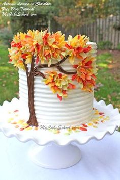 a white cake decorated with leaves and a tree