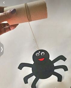 a hand holding a piece of paper with a spider on it