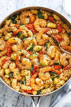 pasta with shrimp, tomatoes and spinach in a white bowl on a gray surface