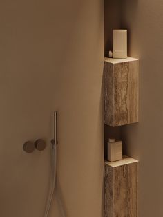 a bathroom with a shower head, soap dispenser and shelf