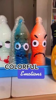 three plastic bottles with faces painted on them and the words colorful emotions in front of them