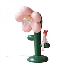 a pink flower lamp sitting on top of a green table next to a small figure