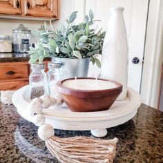 a table topped with a bowl and vase filled with plants on top of a counter