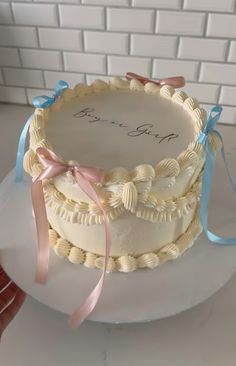 there is a wedding cake with ribbons on the top and bottom layer, decorated with shells