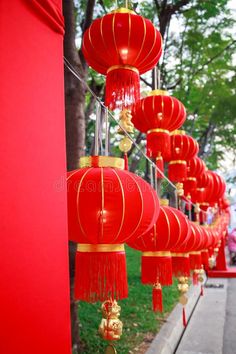 many red lanterns hanging from the side of a building with gold trimmings and tassels