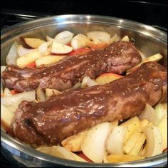 two meats and onions in a pan on the stove top, ready to be cooked