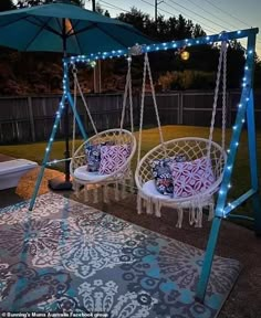 two hanging chairs with lights on them in the back yard, one is white and the other is blue