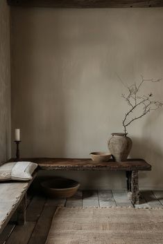 a table with a vase on it in front of a wall and a rug next to it