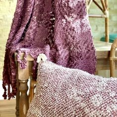 a close up of a pillow on a chair with a blanket draped over the back