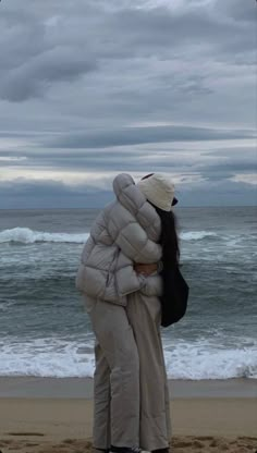 two people hugging each other on the beach