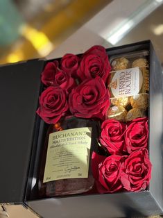 a box filled with lots of red roses next to a bottle of boojute