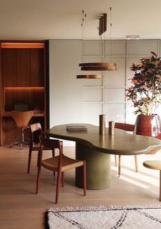 a dining room table surrounded by chairs and vases with plants on them in the corner