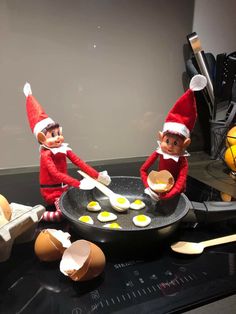 two elfs frying eggs in a pan on the stove