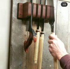 a person holding a pair of scissors in front of a wall mounted rack with several different tools