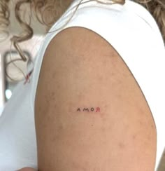 a woman's arm with the word roma tattooed on her left shoulder, in red ink