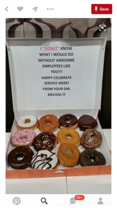 an open box filled with donuts sitting on top of a table next to a sign