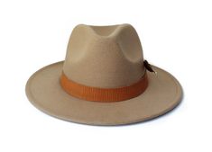 The Rito Hat from the Oaxaca Collection Type: Center Dent Wide Brim FedoraSpecifications: Adjustable Size- With a tie of a knot, adjust the fit of your hat to the ideal size from 21 ¼ to 23 ¼ inches.Dimensions: Wired Brim: 2 7/8", Crown: 4"Color: CamelMaterials: 65% Cotton , 35% Polyester Vegan leather hat bandTurkey featherOrigin: All of our hats begin in Ecuador as the body is molded, then completed in Tucson, AZ where they are shaped, trimmed and designed with artisanal hatbands, leather good Adjustable Wide Brim Panama Hat For Winter, Winter Adjustable Wide Brim Panama Hat, Adjustable Fit Beige Hat With Flat Brim, Beige Flat Brim Hat With Adjustable Fit, Adjustable Solid Felt Hat With Flat Brim, Elegant Adjustable Sun Hat With Flat Bill, Elegant Adjustable Flat Bill Sun Hat, Elegant Adjustable Flat Bill Hat, Adjustable Curved Brim Panama Hat For Fall