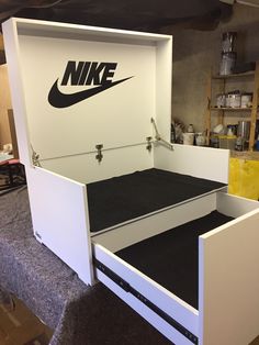 a white box with a nike logo on the lid and bottom drawer opened to reveal a bed