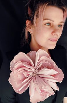 a woman wearing a black shirt and pink flower in her hair, looking at the camera