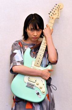 a woman holding an electric guitar up to her face